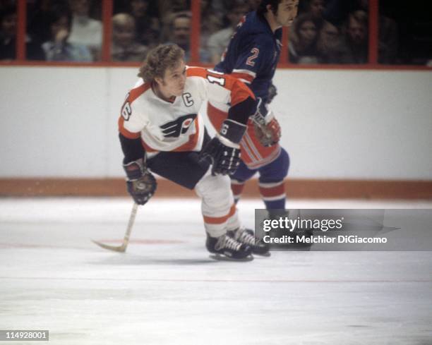 Bobby Clarke of the Philadelphia Flyers and Brad Park of the New York Rangers skate on the ice during an NHL game circa 1975 at the Spectrum in...