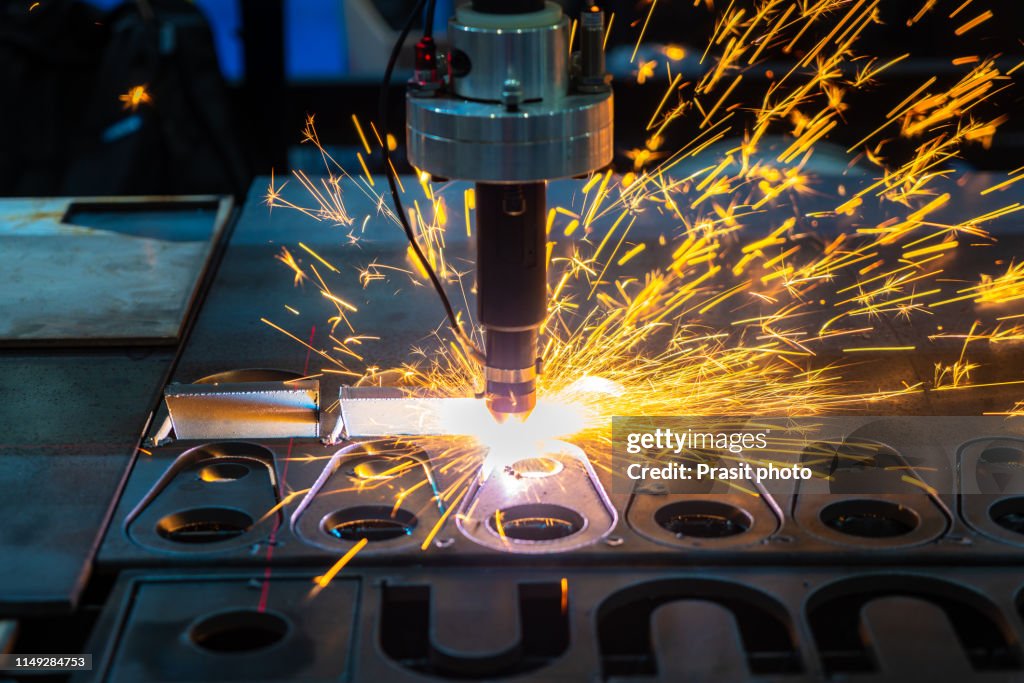 The fiber laser cutting machine cutting the sheet metal plate with the sparking light. Hi-technology manufacturing concept.