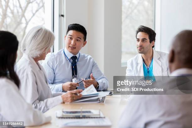 male hospital administrator talks with female doctor - hospital leadership stock pictures, royalty-free photos & images
