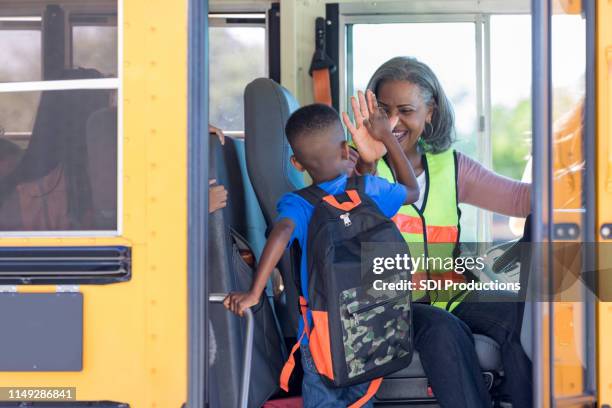 bus driver high fives new student stepping on bus - bus driver stock pictures, royalty-free photos & images