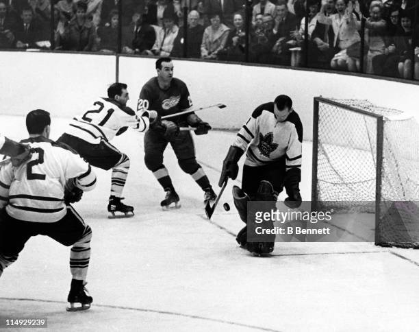 Goalie Johnny Bower of the Toronto Maple Leafs makes the save as his teammates Bobby Baun and Carl Brewer box out Paker MacDonald of the Detroit Red...