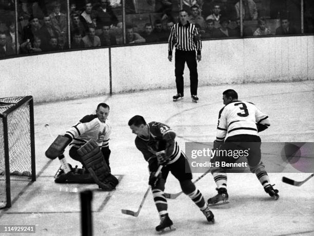 Goalie Johnny Bower of the Toronto Maple Leafs looks to make the save against Stan Mikita of the Chicago Blackhawks as Bower's teammate Marcel...