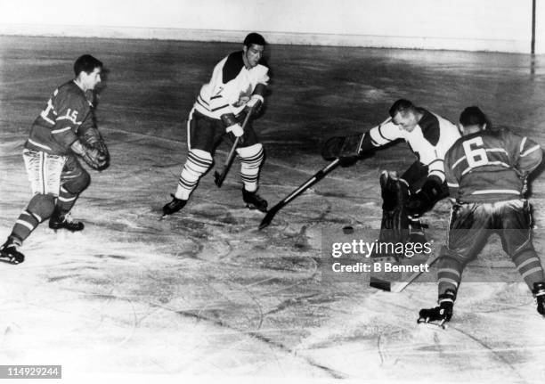 Goalie Johnny Bower of the Toronto Maple Leafs makes the save as his teammate Tim Horton tries to help with the rebound as Bob Rousseau and Ralph...