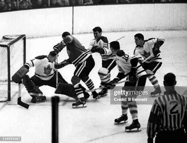 Goalie Johnny Bower of the Toronto Maple Leafs makes the save on Ken Hodge of the Chicago Blackhawks as George Armstrong, Tim Horton and Allan...