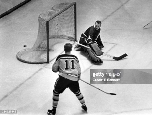 Goalie Johnny Bower of the Toronto Maple Leafs made the save against Tommy Williams of the Boston Bruins as the puck ended up behind the net during...