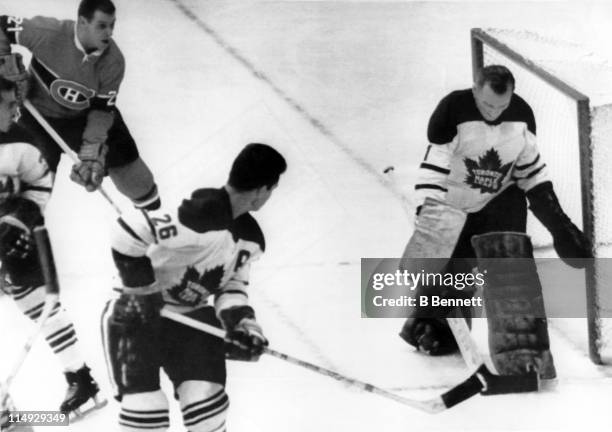 Goalie Johnny Bower of the Toronto Maple Leafs makes the save as his teammate Allan Stanley and Gilles Tremblay of the Montreal Canadiens look for...