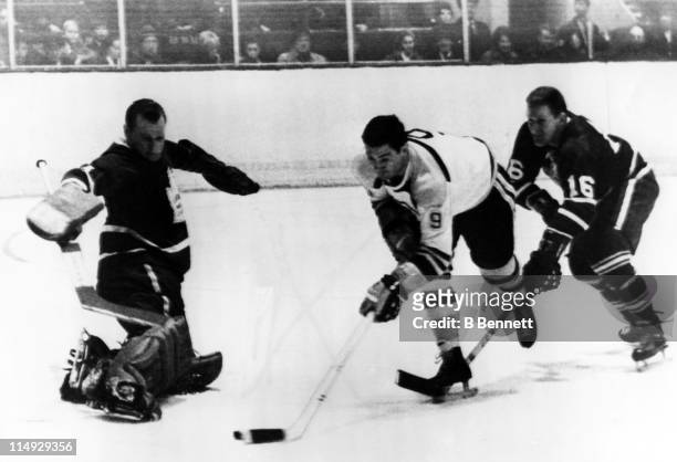 Mike Walton of the Toronto Maple Leafs attempts to stop John Bucyk of the Boston Bruins from shooting the puck as goalie Johnny Bower of the Maple...