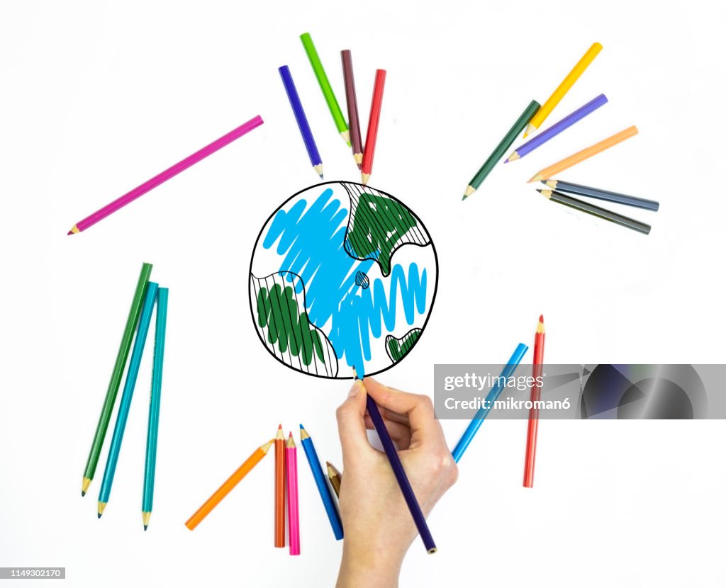 Hand using coloring pencils drawing world