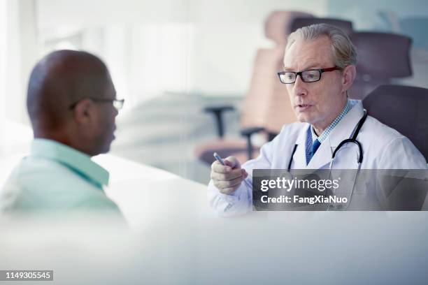 doctor talking to patient at desk in office - critical illness stock pictures, royalty-free photos & images