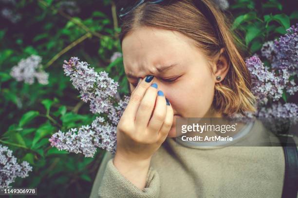 girl with allergy sneezing and cleaning nose in park near blooming flowers in springtime - snorted stock pictures, royalty-free photos & images