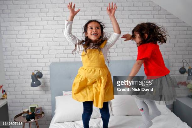 Two friends jumping on bed together