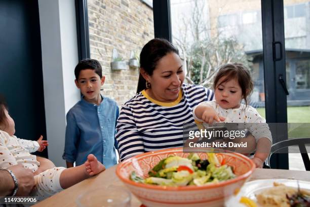 Latin American woman using mobile phone in kitchen with daughter on lap
