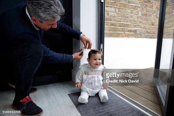 Father measuring baby daughter on floor with ruler