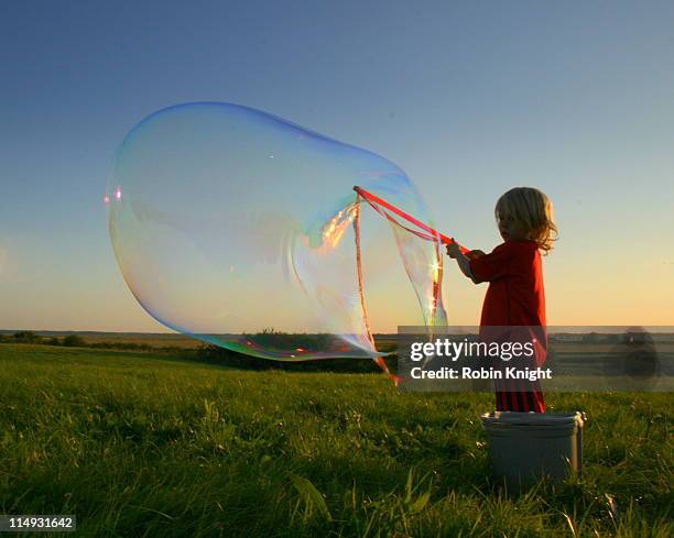 young boy blows large soap bubble - bubbles stock pictures, royalty-free photos & images