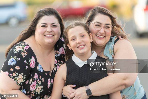 twee mid volwassen vrouwen poseren met een tien jaar oud kind meisje - fat lesbian stockfoto's en -beelden