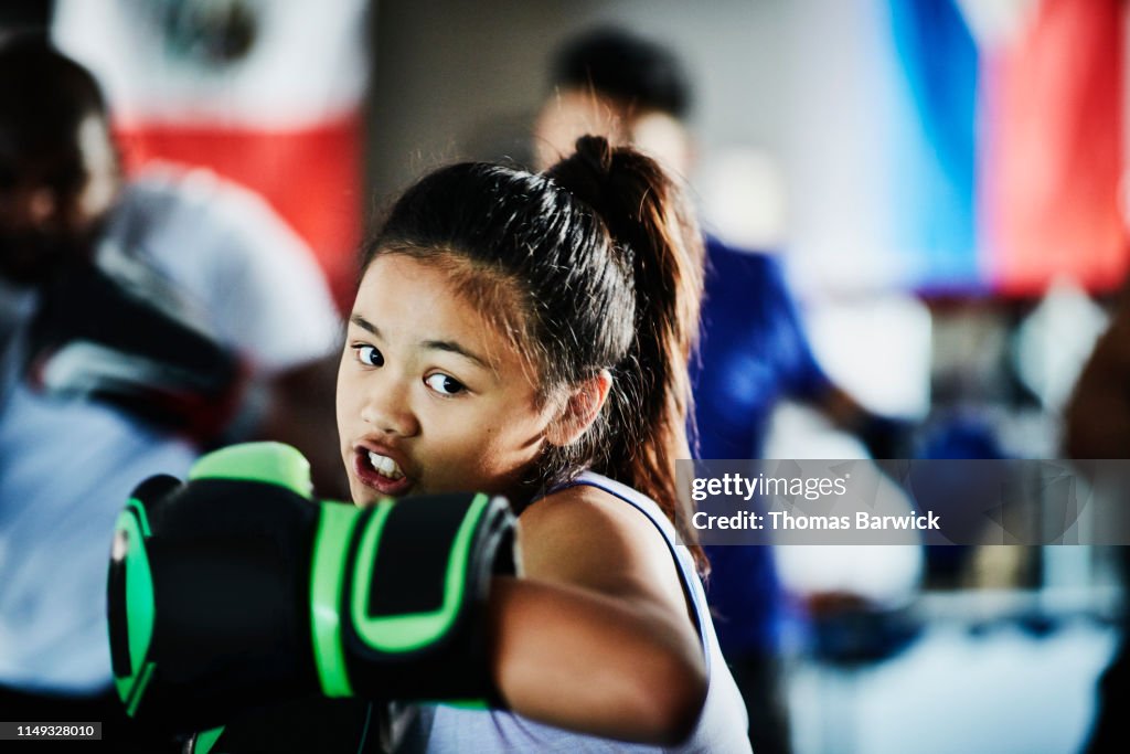 Young female boxer shadow boxing while training in gym