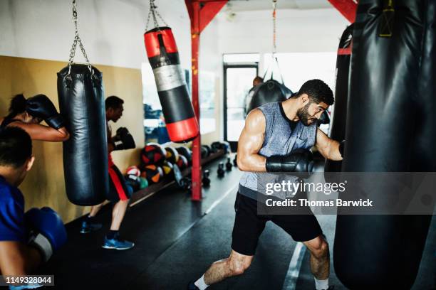 male and female boxers working out on heavy bags during training session in boxing gym - boxboll bildbanksfoton och bilder