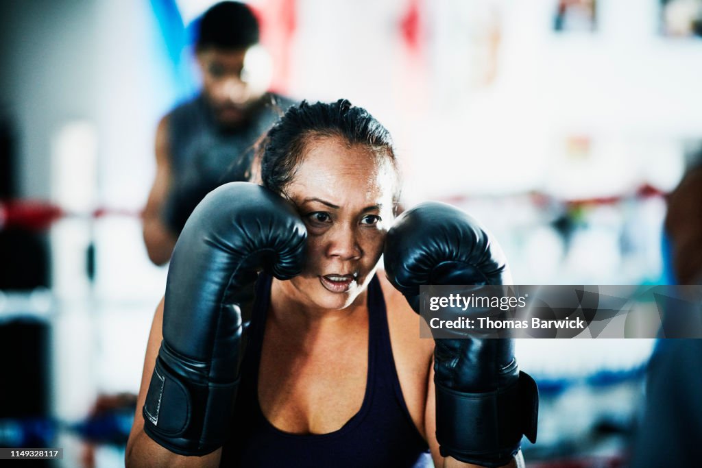 Female boxer training in boxing ring in gym