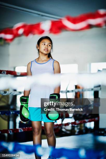 Portrait of young female boxer standing in boxing ring during training session