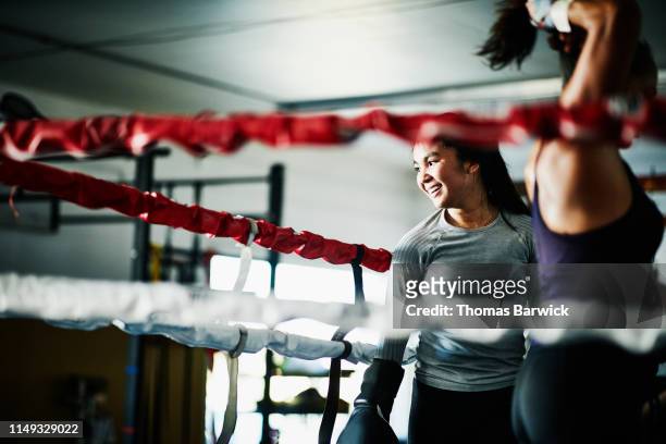Smiling female boxer working out in boxing ring in gym