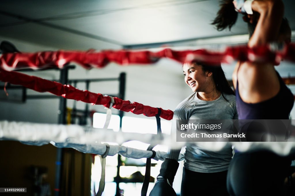 Smiling female boxer working out in boxing ring in gym