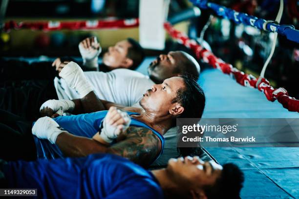 boxers doing crunches together in boxing ring in gym - boxing training stock pictures, royalty-free photos & images