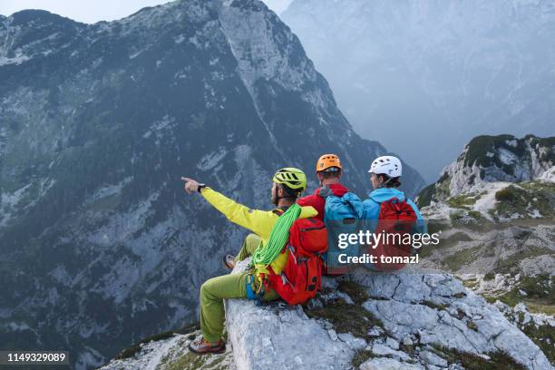 drei bergsteiger sitzen auf dem gipfel des berges mit blick - bergsteiger gruppe stock-fotos und bilder