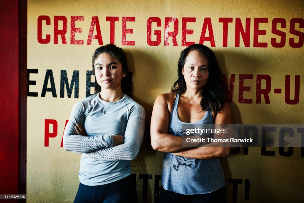 Portrait of female boxers leaning against wall in boxing gym