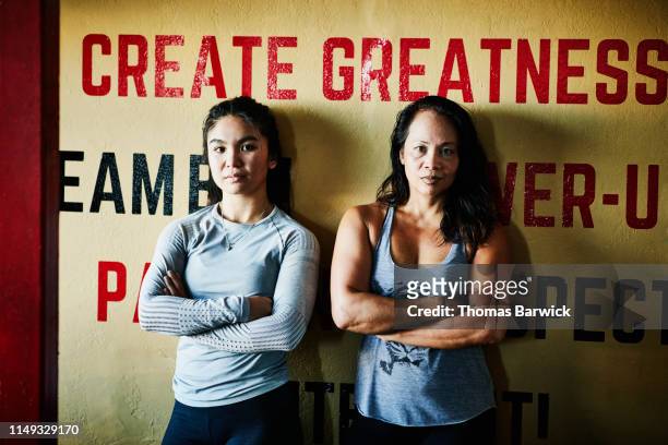 Portrait of female boxers leaning against wall in boxing gym