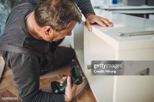 senior handyman assembling wooden furniture - building shelves stock pictures, royalty-free photos & images