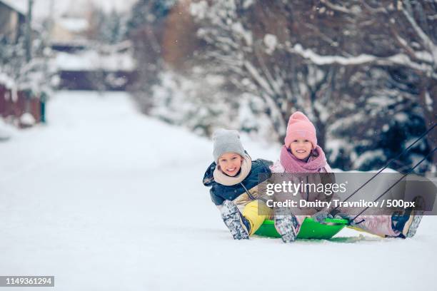 adorable little happy girls sledding in winter snowy day - european best pictures of the day december 8 2014 stock-fotos und bilder