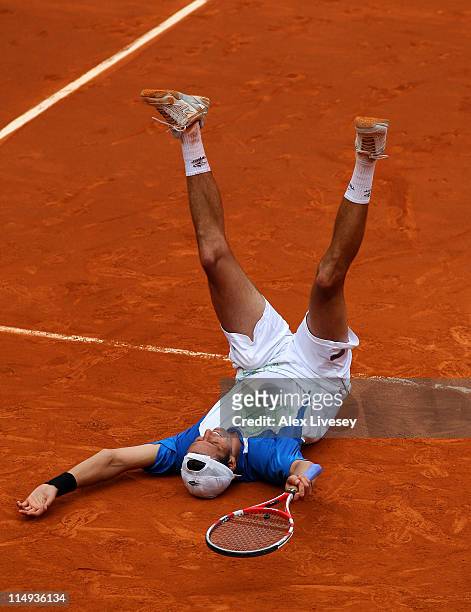 Juan Ignacio Chela of Argentina falls to the court as he celebrates matchpoint during the men's singles round four match between Alejandro Falla of...