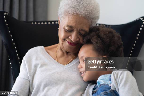 beautiful ethnic grandma is laughing with her young granddaughter. - granddaughter hug stock pictures, royalty-free photos & images