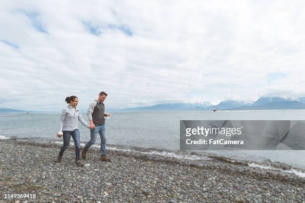 young couple walking along a rocky ocean bay - homer ak stock pictures, royalty-free photos & images