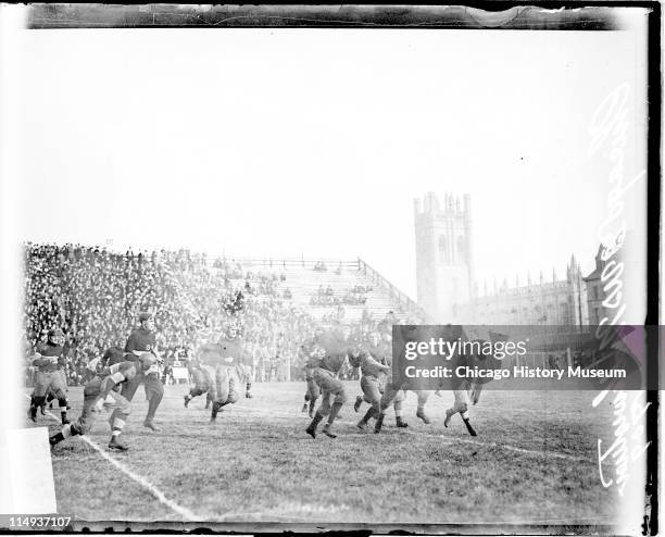 View of a football player holding a football, running on the field during a football game between the University of Chicago and Northwestern...