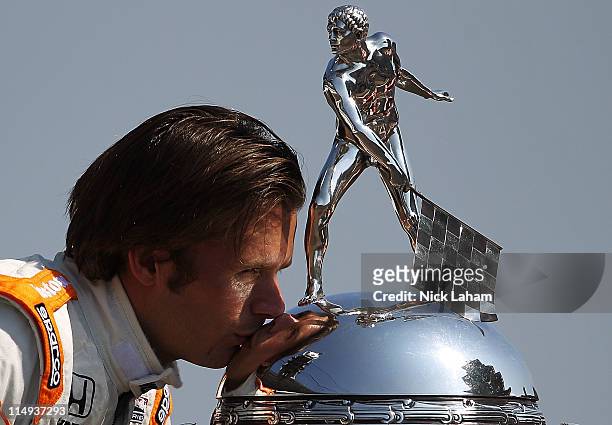 Dan Wheldon of England, driver of the William Rast-Curb/Big Machine Dallara Honda kisses the Borg Warner Trophy on the yard of bricks during the 95th...