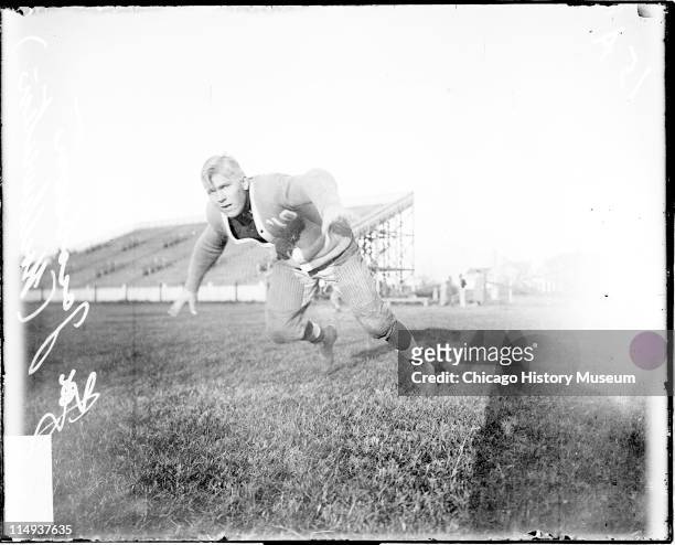 Informal full-length portrait of Northwestern University football player Jacobson lunging forward on an athletic field in or near Evanston, Illinois,...