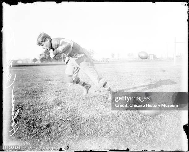 Informal full-length portrait of Northwestern University football player Holmes running in profile on an athletic field in or near Evanston,...