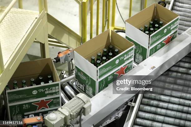 Boxes containing bottles of Heineken NV brand beer, featuring labels with the Web Ellis Cup, move along the production line of a Kirin Brewery Co....