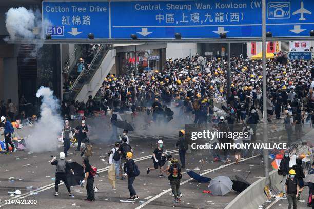 Protesters react after police fired tear gas during a rally against a controversial extradition law proposal outside the government headquarters in...