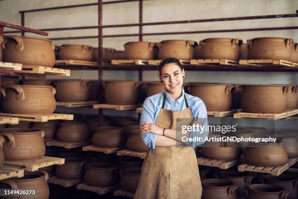 portret van een glimlachende jonge vrouw in een keramische studio. - ambachtsman stockfoto's en -beelden