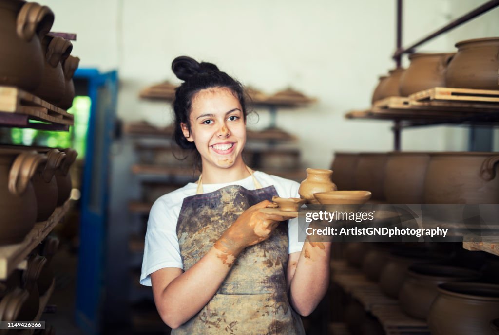 Portrait de l’adolescent retenant des récipients d’argile à l’atelier.