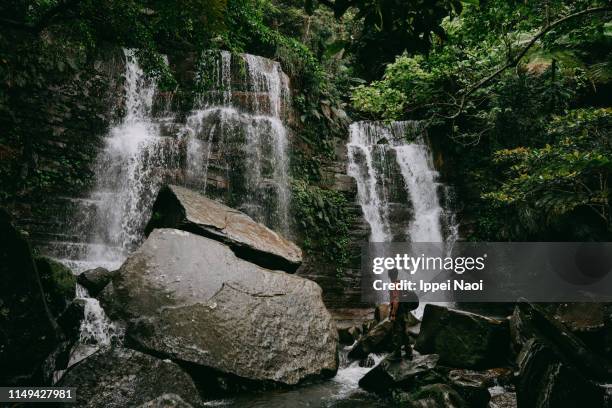 hiker with waterfall in jungle, iriomote island, okinawa, japan - behind waterfall stock-fotos und bilder