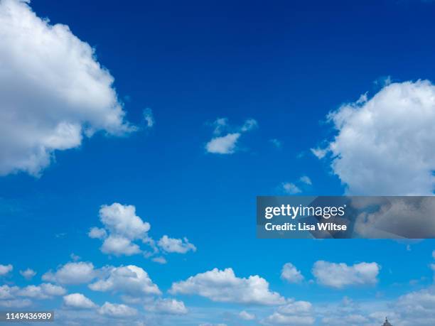 clouds in a bright blue sky - cumulus stockfoto's en -beelden