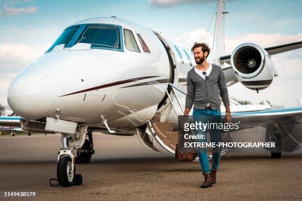 erfolgreicher mann, der von einem privatflugzeug entfernt ist, das auf einem taxi-tageweg geparkt ist - privatflugzeug stock-fotos und bilder