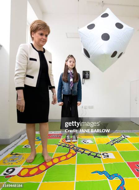 Scotland's First Minister Nicola Sturgeon plays a 'snakes and ladders' game with nine-year-old Ava Dewar during her visit to the Dundee Carers Centre...