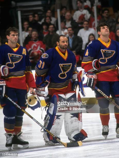 Goalie Grant Fuhr of the St. Louis Blues stands between teammates Pierre Turgeon and Marc Bergevin during the national anthem before their game...