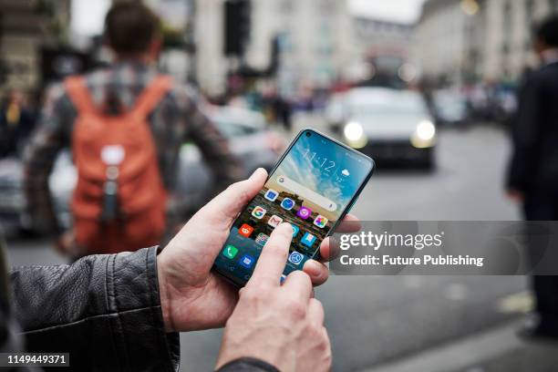 Detail of a man holding up an Honor 20 Pro smartphone while waiting to cross the street, on June 4, 2019.