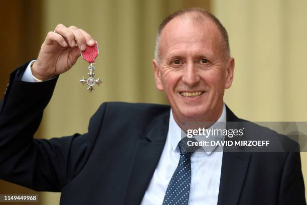 British rescue diver Vernon Unsworth poses with his medal after being appointed a Member of the Order of the British Empire during an investiture...