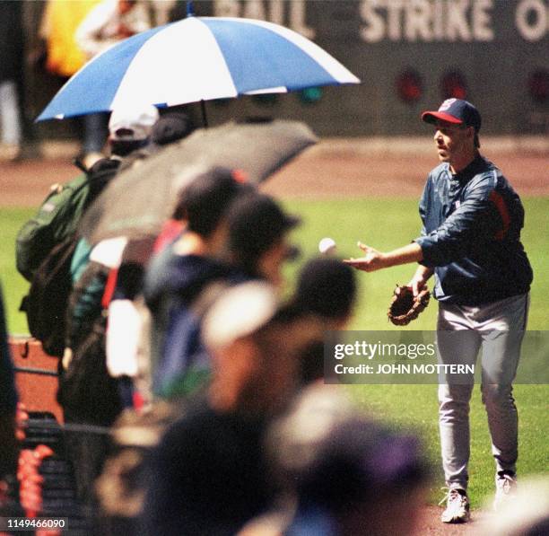 Relief pitcher for the Cleveland Indians Paul Assenmacher tosses a ball to fans under rainy skys and only half the stadium lights turned on at Fenway...